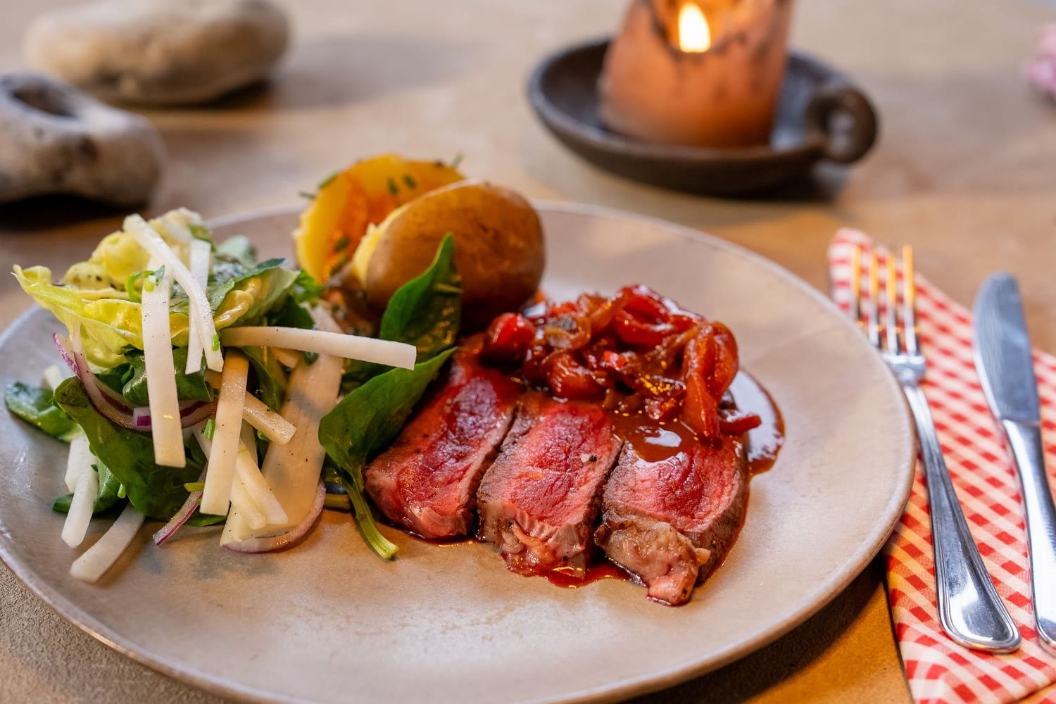 Bord met rosé gebakken steak, salade, aardappelen en tomatensaus