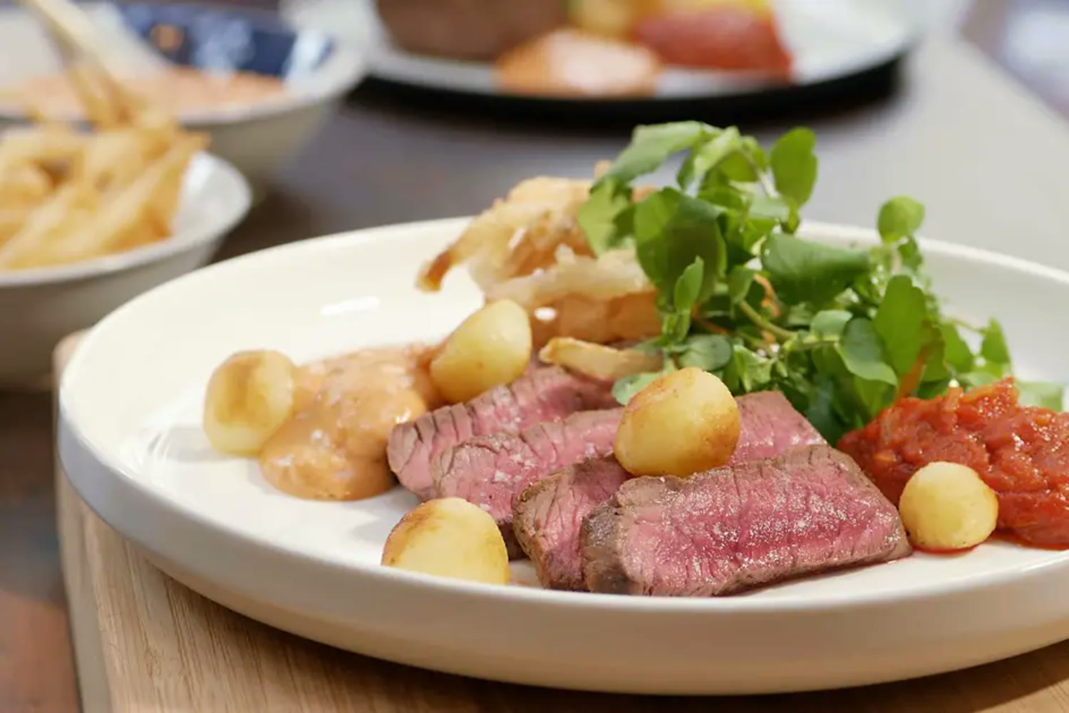 Bord met rosé steak, krieltjes, groene salade en twee sauzen