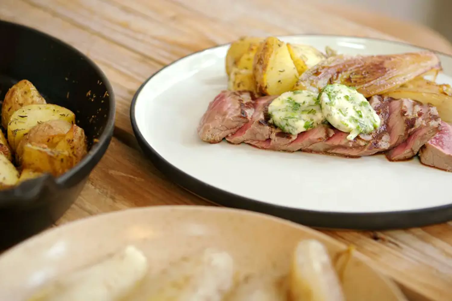Gesneden steak met kruidenboter en gebakken aardappelen op tafel
