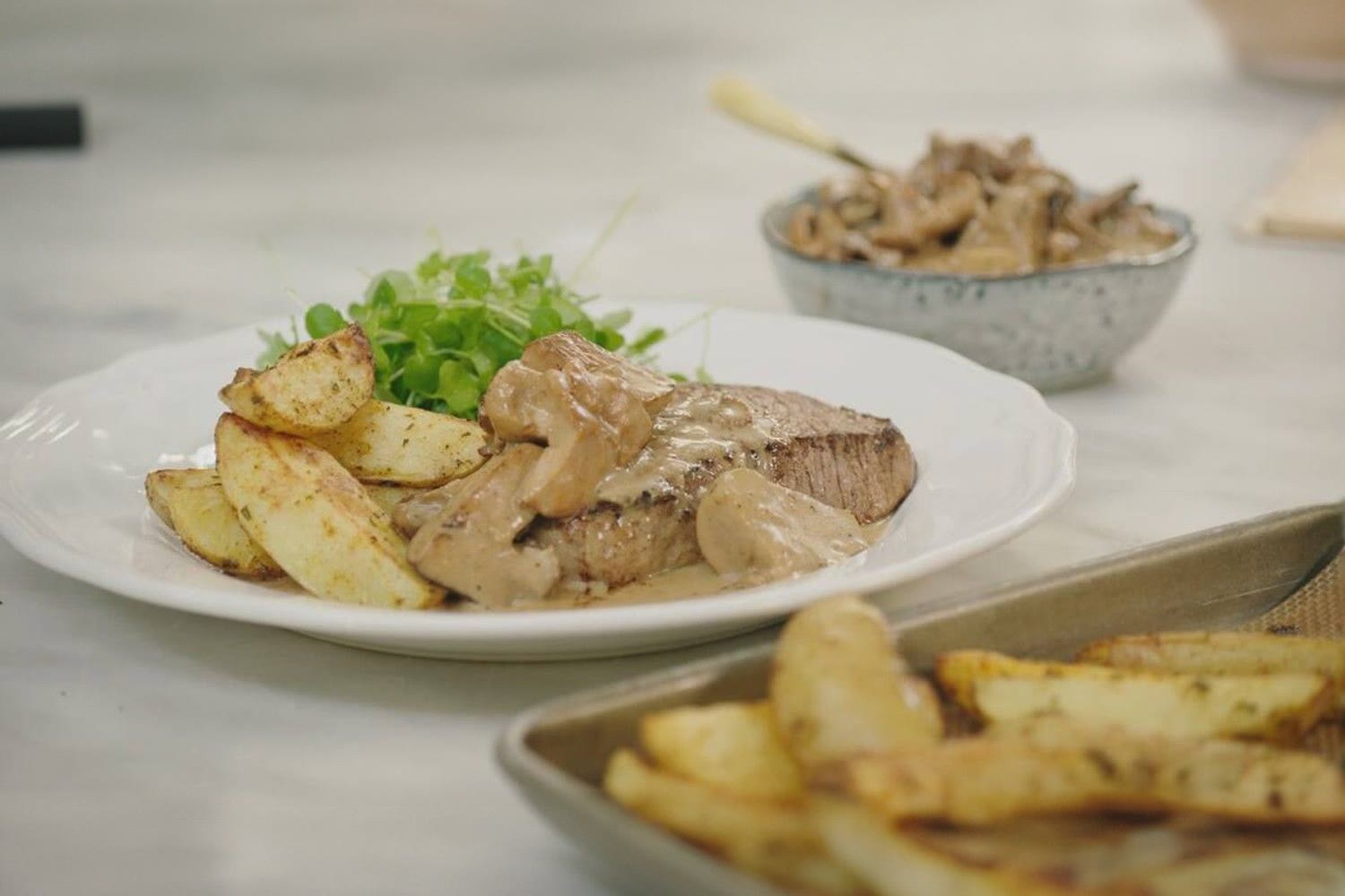 Steak met champignonsaus, aardappelwedges en groene salade