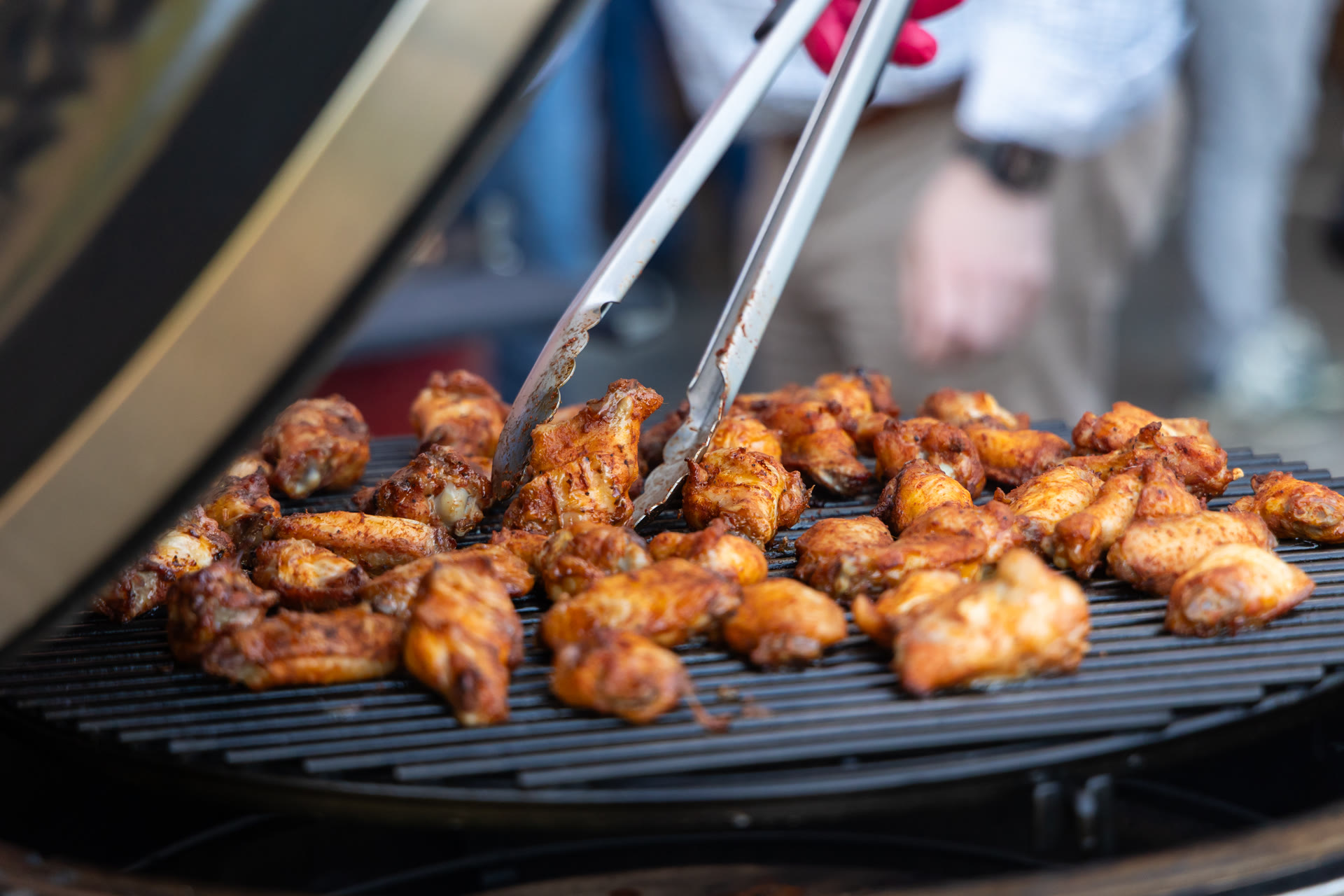 Kippenvleugels worden met een tang op het rooster van de kamado gedraaid